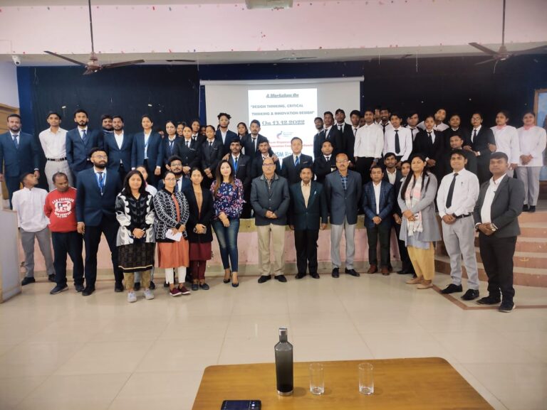 Students and guests posing in front of an event presentation at ISM Ranchi