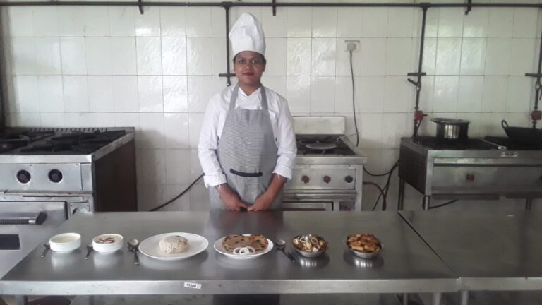 A hotel management student in chef uniform standing in an ISM Ranchi training kitchen