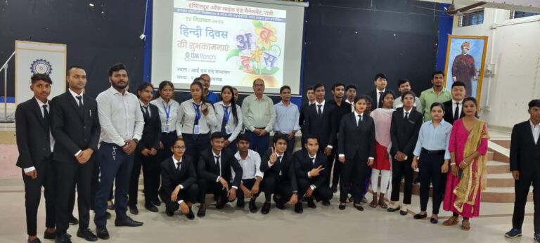 Students and faculty posing in front of a projected event presentation at ISM Ranchi