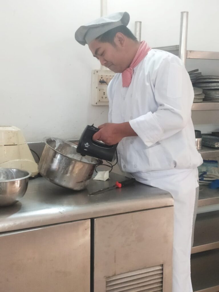 A hotel management student preparing food during an ISM Ranchi practical session